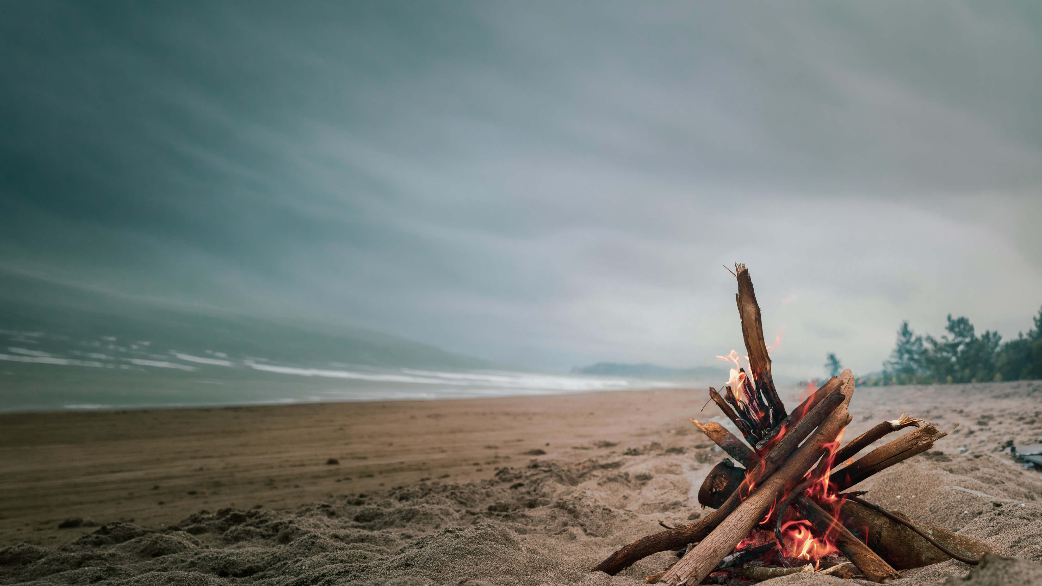 Beach bonfire at night with people gathered around