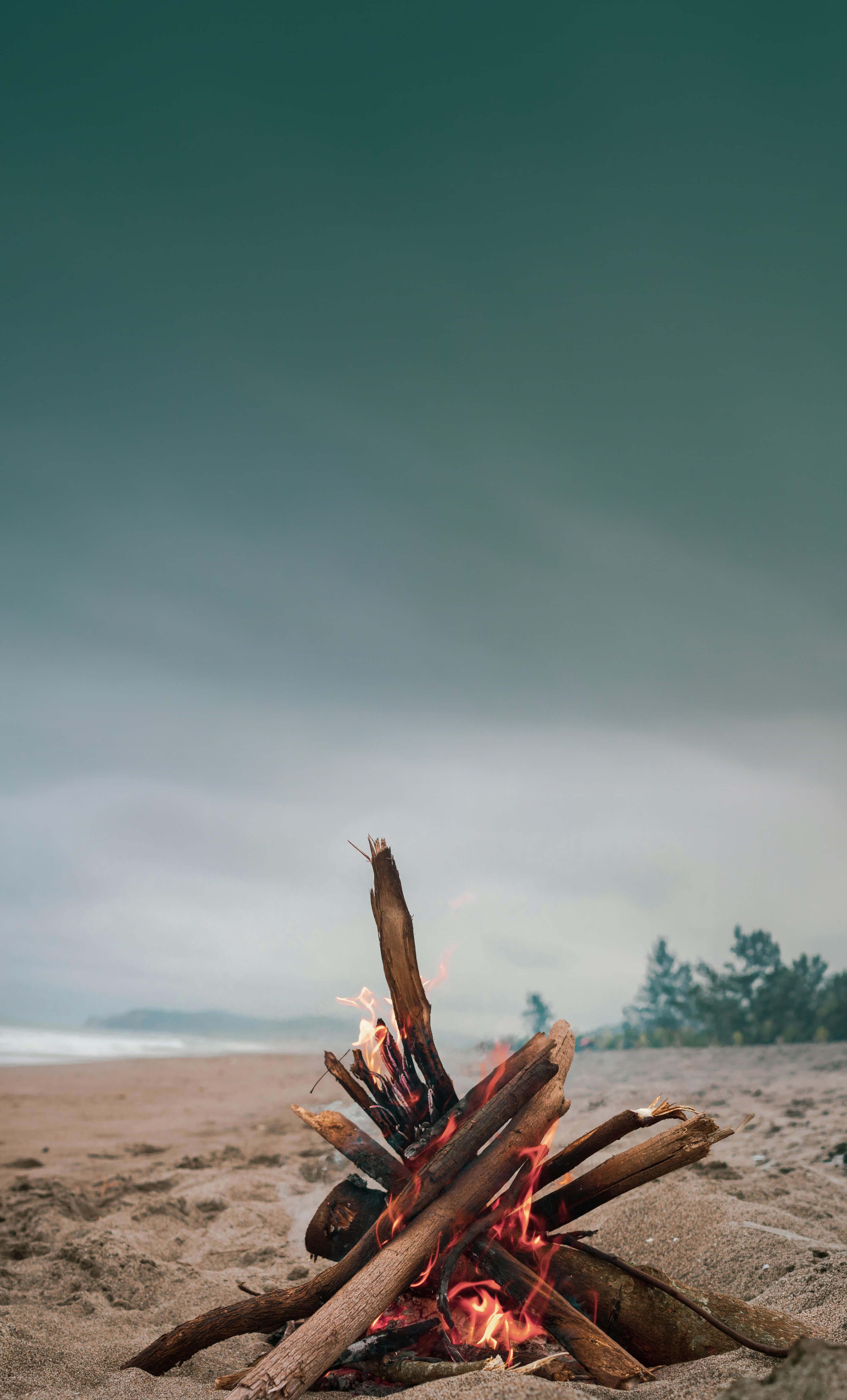Beach bonfire at night with people gathered around